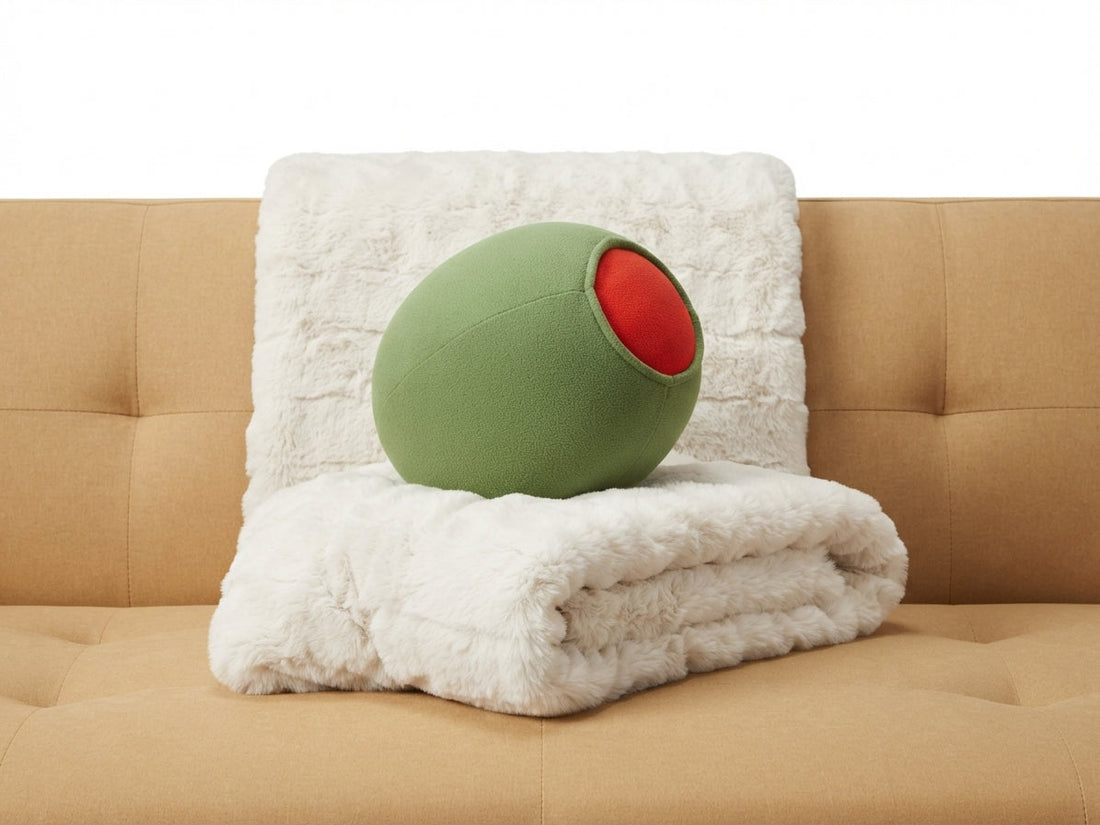Martini olive plush pillow on a white faux-fur throw on a tan sofa, a funny Christmas hostess gift