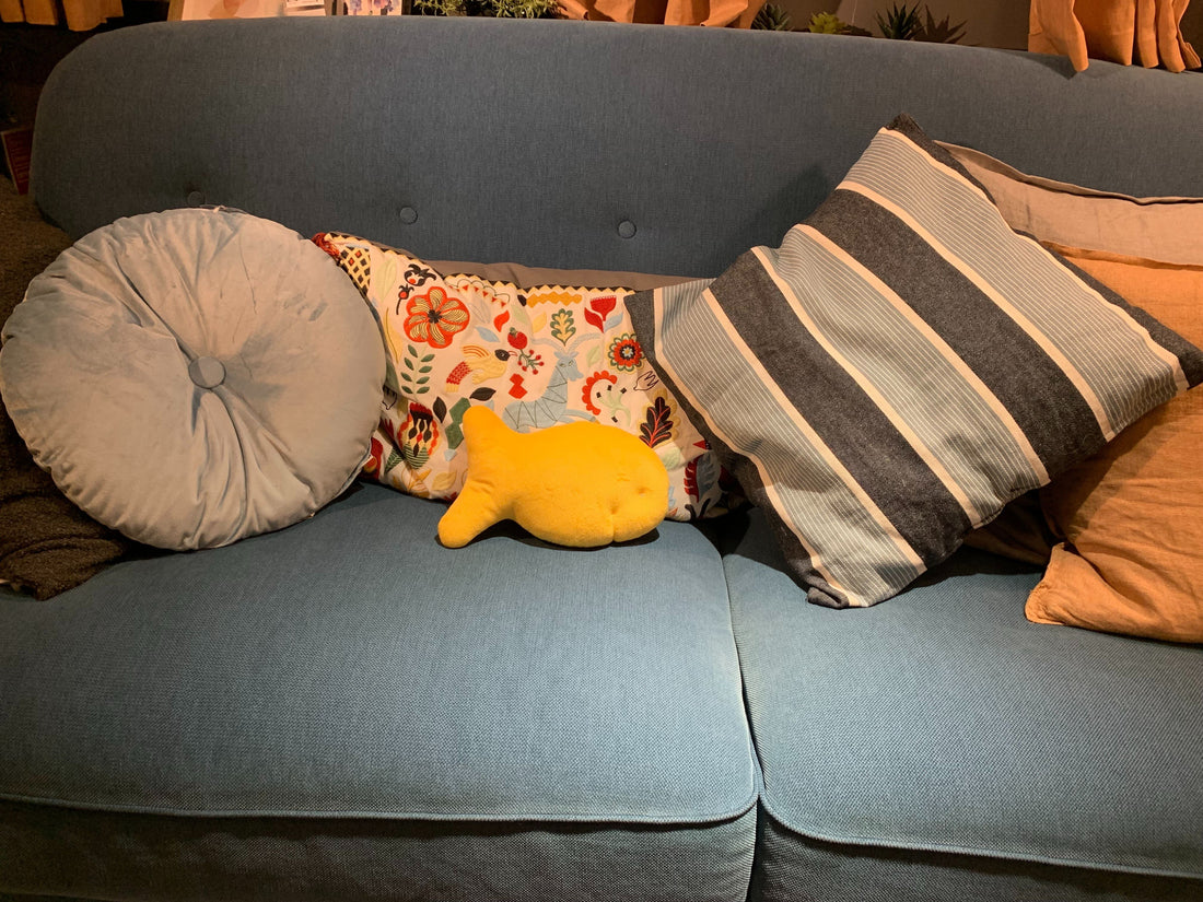 Cheddar fish cracker plush on a blue couch with throw pillows, a gift for snack lovers