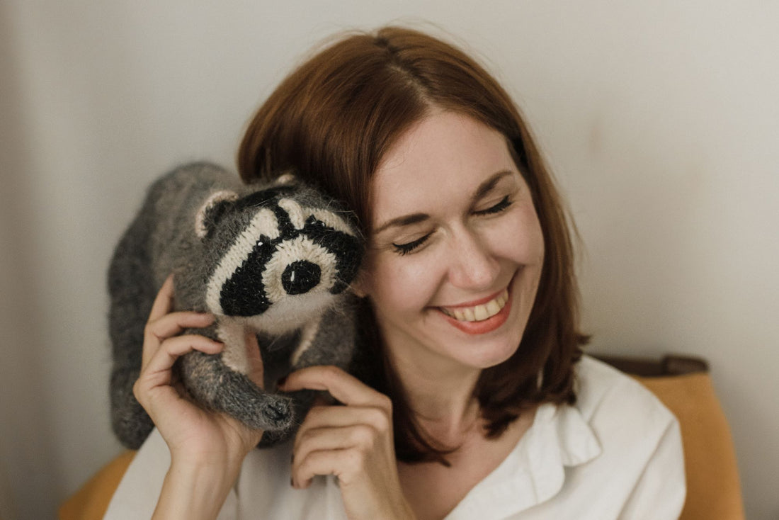 Smiling woman hugging a soft plush toy to her cheek
