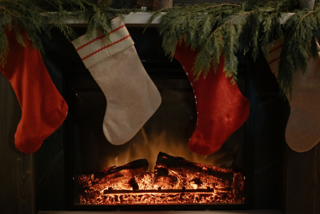 Christmas stockings hanging from a garland-covered mantel above a glowing fireplace