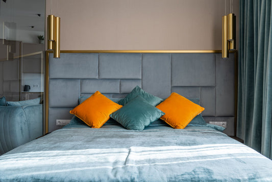 Bed styled with orange and teal throw pillows