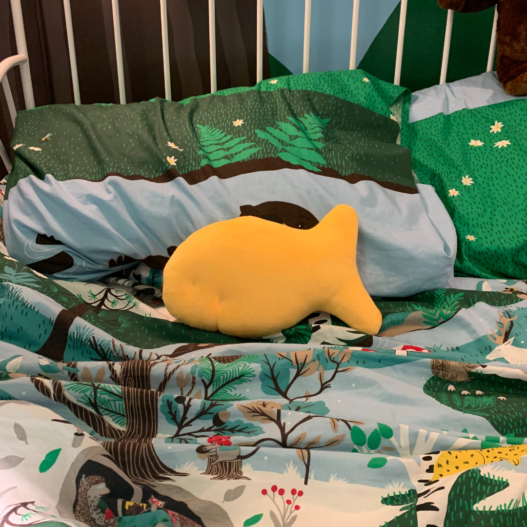 Cheddar fish cracker plush on a colorful children's bed