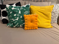 Cheese cracker plush pillow styled with green and yellow throw pillows on a bed